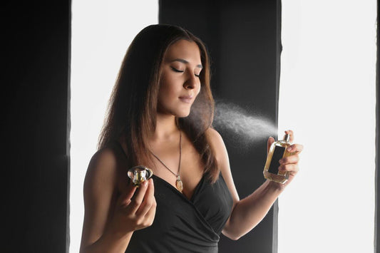 A woman in black spraying a perfume